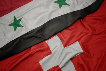 waving colorful flag of switzerland and national flag of syria.