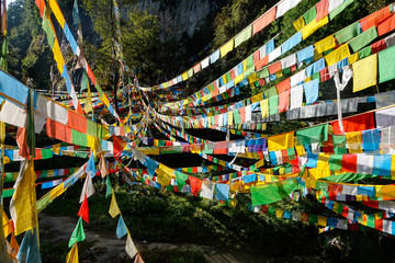 CLOSE UP: Colorful prayer flags span above a walkway in the scenic Tibetan hills