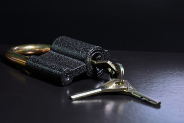 Lock with keys on a black background. Metal padlock close-up.