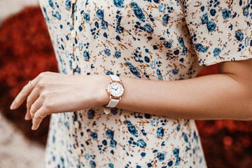 Street style, fashion, trendy summer woman`s outfit, details concept: white elegant wrist watch on hand with reptile textured leather strap, blue floral print dress
