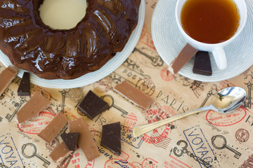 Round chocolate cake with chocolate topping on white plate with tea spoon and pieces of milk and...