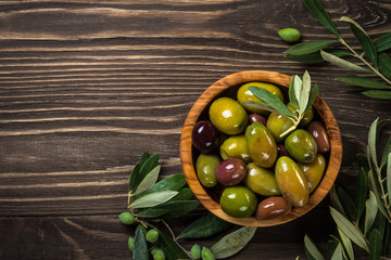 Black and green olives on wooden table.