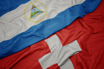 waving colorful flag of switzerland and national flag of nicaragua.