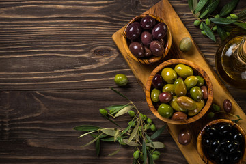Black and green olives on wooden table.