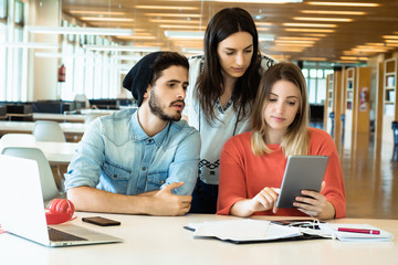 University students using digital tablet in university library.