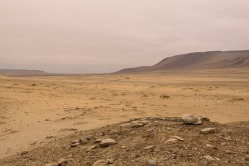 Yellow sand dunes and red mountains in the desert of Paracas National Reserve, Peru