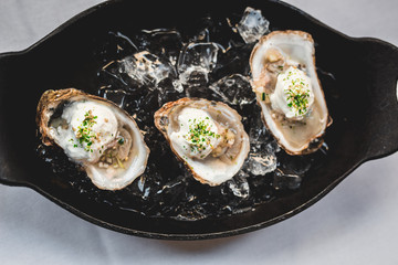 Raw oyster with mignonette sauce, celery & cream in cast iron on ice