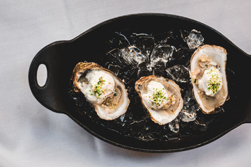 Raw oyster with mignonette sauce, celery & cream in cast iron on ice