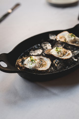 Raw oyster with mignonette sauce, celery & cream in cast iron on ice