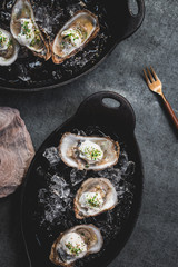 Raw oyster with mignonette sauce, celery & cream in cast iron on ice