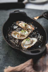 Raw oyster with mignonette sauce, celery & cream in cast iron on ice
