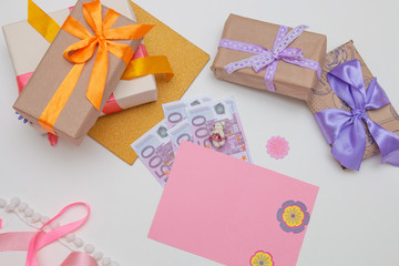 gifts boxes with bright ribbons and bows on a white background pink card, money, dollar bills, euros, copy place, top view, birthday, thanksgiving, holiday, new year, christmas, flat lay