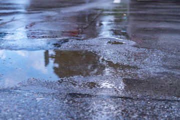 close up puddle on the asphalt with reflections after the rain in the city