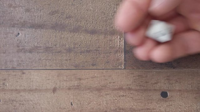 Hand rolls a D8 landing on a 4. Flat lay brown wooden background, 4k slow.