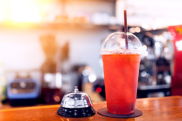 Iced honey lemon tea Beverage in plastic glass and service bell on the table in cafe,Summer drinks with ice