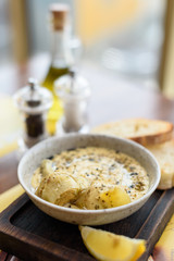 Hummus with dried herbs and canned artichokes in bowl on wooden board