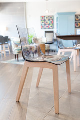 Modern clear acrylic chair with wooden legs at table, hotel cafe