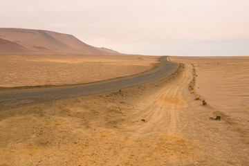 Yellow sand dunes and red mountains in the desert of Paracas National Reserve, Peru