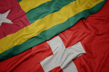 waving colorful flag of switzerland and national flag of togo.