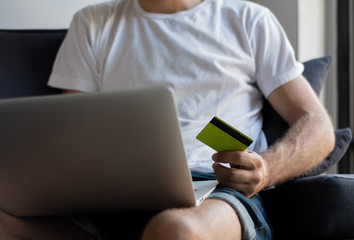 Man with laptop and credit card at home.