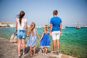 Parents and kids at street of typical greek traditional village on Mykonos Island, in Greece