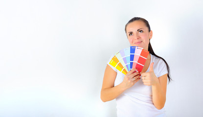 young girl holds a color palette in her hands and chooses a color for repairs in the house, on a white background
