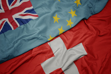 waving colorful flag of switzerland and national flag of Tuvalu .