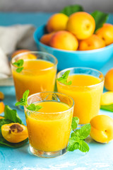 Glass of fresh healthy apricot juice in sunny light on blue surface