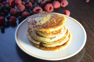 Pancakes with berries and maple syrup with raspberries and blueberries on a black background