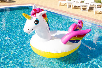 Inflatable colorful unicorn at the swimming pool. Vacation time in the swim pool with plastic toys. Relaxation and fun concept