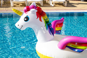 Head of unicorn swim tube on pool background. Summer holidays, beach vacation. Fantasy swim ring....