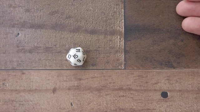 Rolling a 15 on 20 sided die. 4k, flat lay, closeup, wood background.