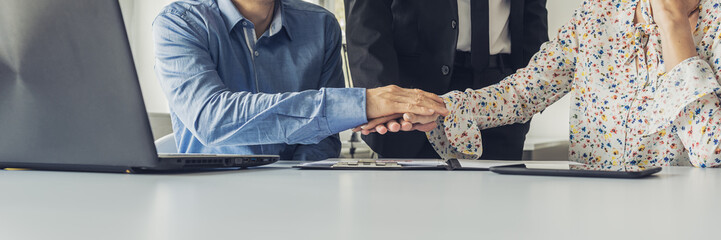 Three business people stacking their hands