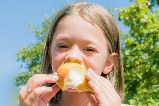 Little girl eating fresh pear