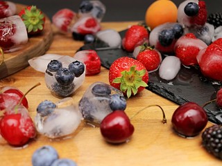 Photoshoot from mixed fruits with ice cubes on table. strawberries, apricots, raspberries, blueberries, blackberries, red cherries, top view