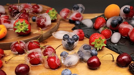 Photoshoot from mixed fruits with ice cubes on table. strawberries, apricots, raspberries, blueberries, blackberries, red cherries, top view