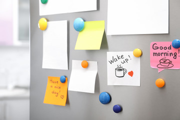 Many notes and empty sheets with magnets on refrigerator door in kitchen. Space for text