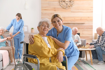 Nurse with elderly woman in wheelchair at retirement home. Assisting senior people - obrazy, fototapety, plakaty