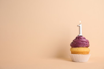 Birthday cupcake with number one candle on beige background, space for text