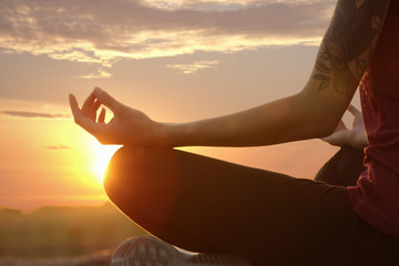 Young woman practicing zen yoga at sunrise outdoors, closeup