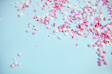Colorful sprinkles on blue background, top view with copy space