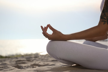 Fototapeta na wymiar Young woman practicing zen meditation on beach, closeup. Space for text