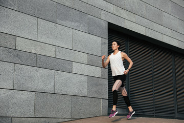 Beautiful sporty young woman running on street, space for text