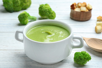 Bowl of broccoli cream soup served on white wooden table