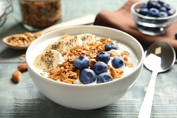 Bowl of yogurt with blueberries, banana and oatmeal on color wooden table - Powered by Adobe
