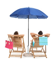 Young couple with beach accessories on sun loungers against white background