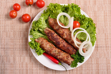 Lula kebab is a traditional Arabic dish. Meat shashlik on  with tomato. The top view