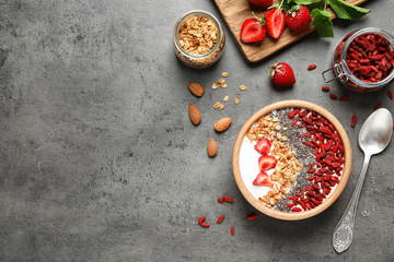 Flat lay composition of smoothie bowl with goji berries on grey table. Space for text