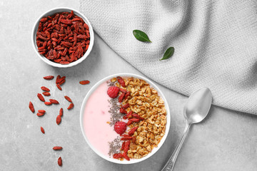 Smoothie bowl with goji berries on grey table, flat lay