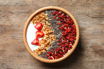 Smoothie bowl with goji berries on wooden table, top view